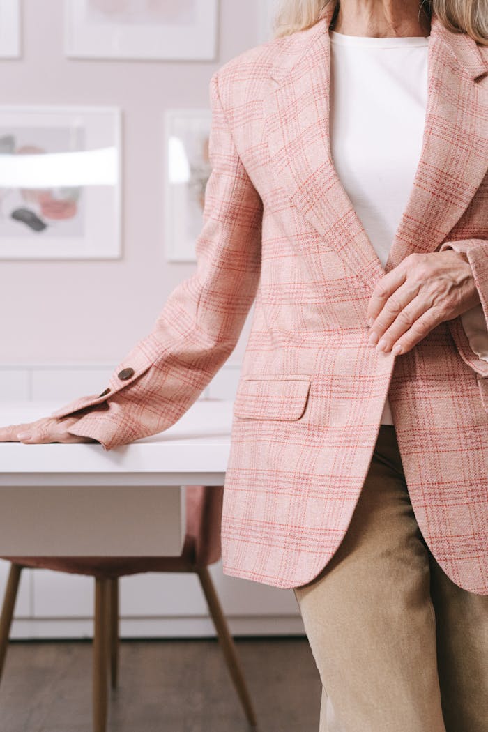 our-services-1 Stylish senior woman in pink plaid blazer standing in a modern home office setting.